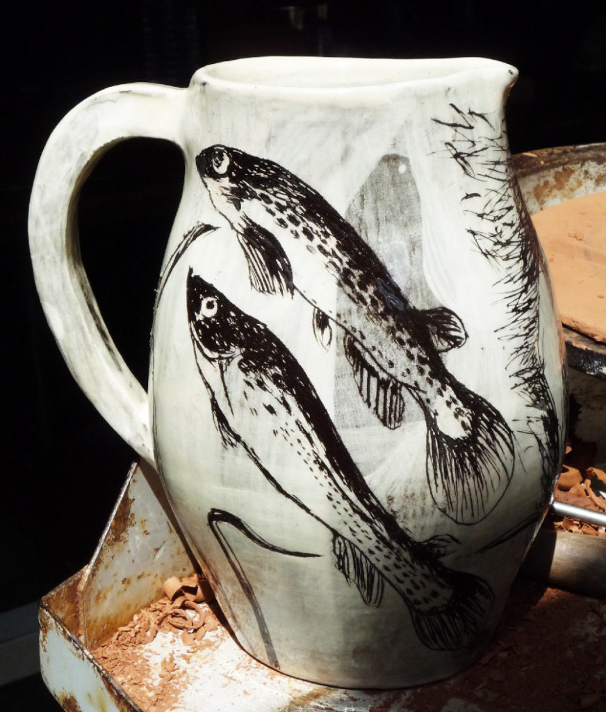 Carafe blanche ornée de poissons dessinés au colorant céramique noir.